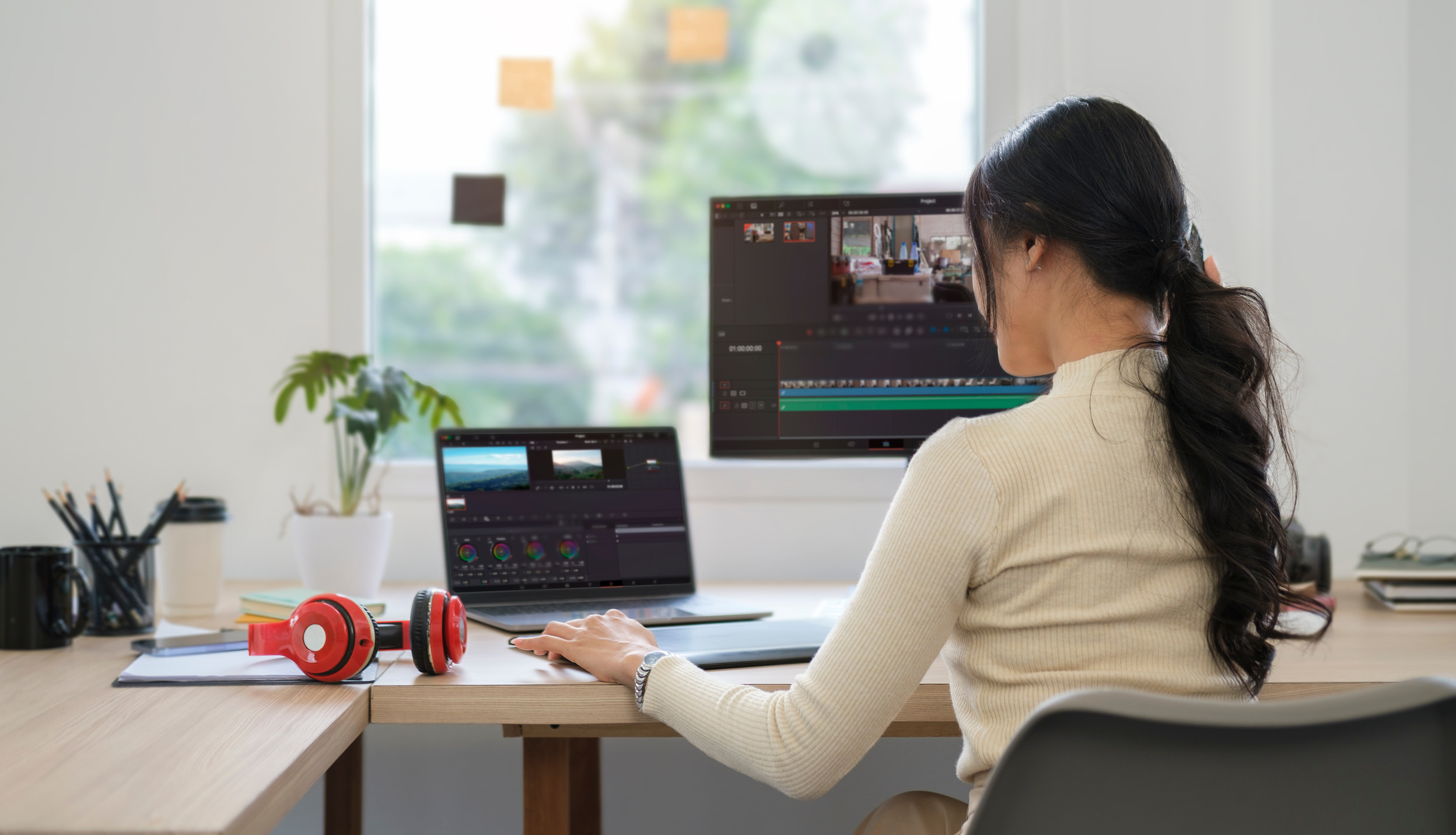 Rear view of young woman editing video footage on professional c